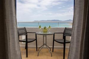 迈加洛丘里日出一室公寓式酒店的阳台上的桌子和椅子，可欣赏海景