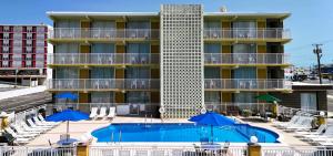 a hotel with a swimming pool and blue umbrellas at Landmark Motel in Wildwood