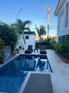 une piscine avec deux chaises à côté d'une maison dans l'établissement Casa de tres habitaciones con piscina, à La Romana