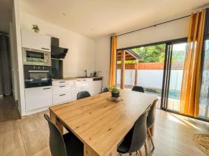 a kitchen with a wooden table and some chairs at La Ŵilla, piscine et parking privatisées, accès mer, sentiers et volcans!! in Saint-Joseph +8 photos