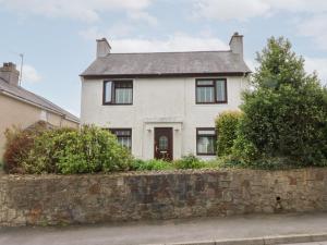 a white house with a stone wall at Fairfield in Pwllheli