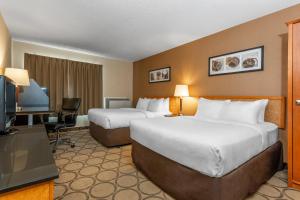 a hotel room with two beds and a flat screen tv at Comfort Inn Regina East in Regina +17 photos