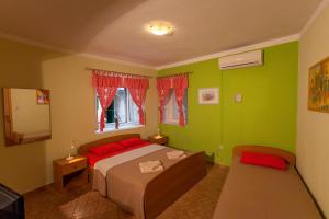 a bedroom with green walls and a bed with red pillows at Guest House Floreus Cres in Cres