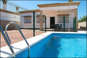 una piscina frente a una casa en Chalet Arroyo Majadales 107, en Conil de la Frontera