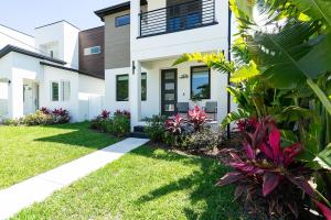 a house with a green yard with plants at Chic & Spacious 4 Bedroom 3 Full Bathrooms Retreat in West Tampa and Pvt Backyard in Tampa