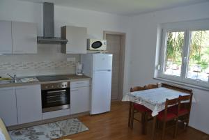 eine Küche mit weißen Geräten und einem Tisch mit Stühlen in der Unterkunft Apartmaji NIKA in Izola