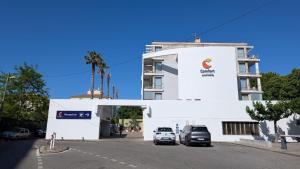 a white building with cars parked in a parking lot at Comfort Aparthotel Marseille Prado in Marseille