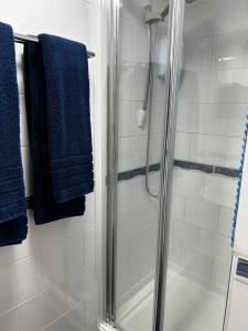 a bathroom with a shower with blue towels at Ortari@70 in Bishopston
