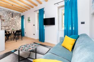 Una sala de estar con un sofá azul y una mesa. en Apartman Grisia, en Rovinj