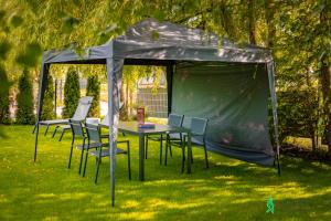 a tent with chairs and a table in the grass at Dom w Starkowie, Sauna i Balia in Starków