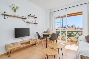 Una sala de estar con televisión, mesa y sillas. en Apartamento Mani, en Nerja