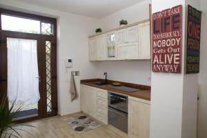 a kitchen with white cabinets and a sign on the wall at Just House in Campagnano di Roma