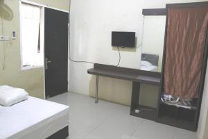 a room with a bed and a desk with a television at OYO Life 2982 Griya Aisyah Residence 2 in Kedurus