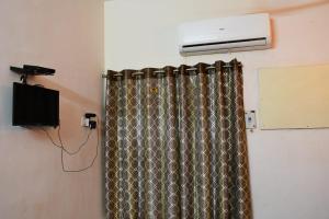 a room with a heater and a curtain and a television at Sai Nalam Guest inn in Chennai