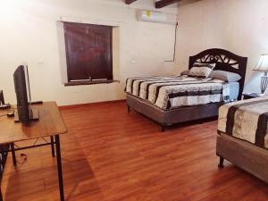 a bedroom with two beds and a desk and a television at Valle de Ángeles Entre Hamacas y Fogatas in Valle de Ángeles