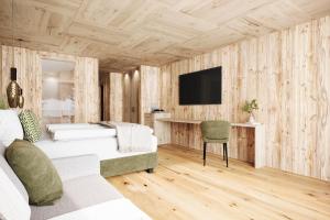 a bedroom with a bed and a tv on a wooden wall at Luxury B&B August in Ortisei