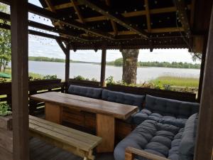 a patio with a table and benches and a lake at Camping "Sīvezers" in Auleja