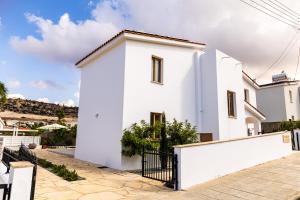 una casa blanca con una valla negra en Villa Cloxania Coral, en Peyia