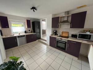 a kitchen with dark purple cabinets and appliances at Ferienhaus Almir in Haselünne +6 photos