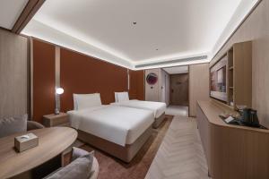 a hotel room with two beds and a television at Orange Crystal Chengdu Financial City South Railway Station Hotel in Chengdu