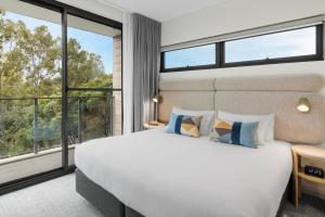 a bedroom with a white bed and a large window at Quest at Sydney Olympic Park in Sydney +51 photos