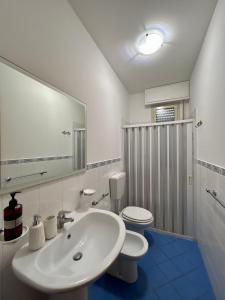Un baño con lavabo, inodoro y espejo. en La Riviera Holiday Home, en Marina di Ragusa