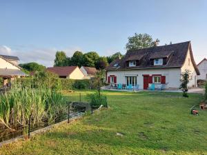 a white house with red doors and a yard at la picarde in Tours-en-Vimeu
