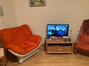 a living room with an orange chair and a tv at Fort Noks with sea view in Elenite