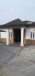 a house with two white columns and a green table at Reyna apartment in Lekki