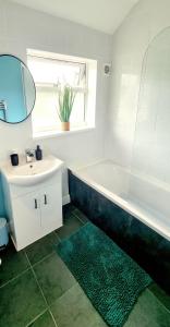une salle de bain avec une baignoire, un lavabo et un miroir dans l'établissement Stunning Lux 3 Bedroom home Priv Parking in Birmingham, à Kings Norton 15 autres photos