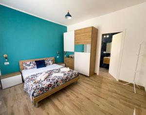 a bedroom with a bed and a blue wall at LA RIVA DEL '44 Apartments - Elegant, spacious, and bright holiday homes just a few steps from Nettuno's finest beach in Nettuno