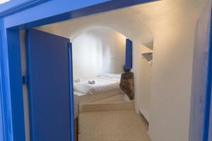 a small room with a bed and a blue door at Gemini Cave Florina in Oia