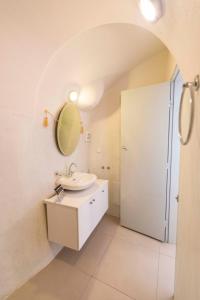 a white bathroom with a sink and a mirror at Gemini Cave Florina in Oia