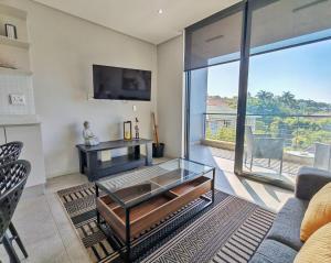 un soggiorno con tavolino in vetro e TV di 707 2six2 Florida Rd- corporate 1 bedroom a Durban