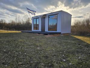 a tiny house sitting on top of a field at Sīvera Medniekkrasti in Stoli