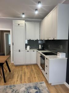 a kitchen with white cabinets and a wooden floor at Apartament Pod Filarami in Zielona Góra