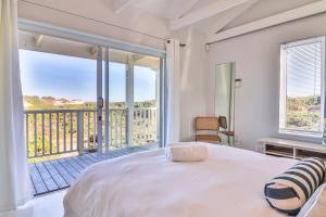 a bedroom with a large bed and a balcony at Nordic Family Beach House in Bettyʼs Bay +43 photos