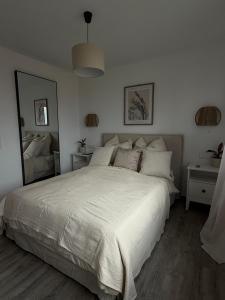 ein Schlafzimmer mit einem weißen Bett und einem großen Spiegel in der Unterkunft Mams-Cottage-Olivia in Harnischdorf