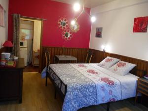 a bedroom with a bed and a red wall at Les Clés du Parc in Combrand