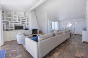 een woonkamer met een bank en een tv bij Casa Maresia da Salema in Salema