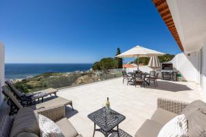 een patio met tafels en een parasol en de oceaan bij Casa Maresia da Salema in Salema