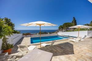een zwembad met twee parasols en stoelen en een zwembad bij Casa Maresia da Salema in Salema