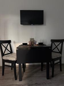 ein schwarzes Klavier mit zwei Stühlen und einem Fernseher an der Wand in der Unterkunft Mams-Cottage-Doris in Harnischdorf