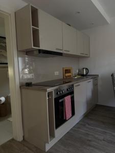 eine Küche mit weißen Schränken und einem Ofen mit einem Handtuch in der Unterkunft Mams-Cottage-Doris in Harnischdorf