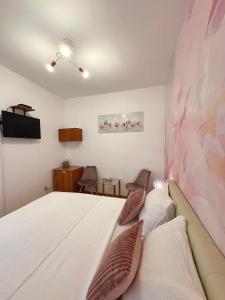 a bedroom with a white bed and a pink wall at Guest House Štorija, Vis Center, 1 min from Ferry in Vis