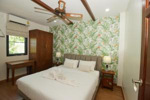 a bedroom with a white bed with a floral wallpaper at Baan Ping Tara Tropical Pool Villa and Scooter in Ban Khlong Son +27 photos