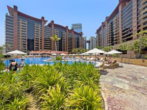 迪拜VayK - Spacious 2BR with Beach Access & Private Gym on Palm Jumeirah的一个带遮阳伞和建筑的游泳池的度假村