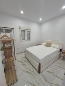 a white bedroom with a bed and a mirror at Casitalola in Conil de la Frontera +18 photos