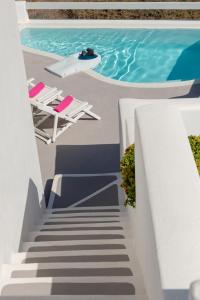 a staircase leading to a pool with chairs and a swimming pool at Aura Marina Apartments Santorini in Akrotiri