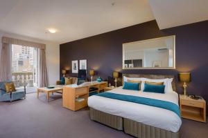 a hotel room with a large bed and a desk at Treasury on Collins Melbourne in Melbourne